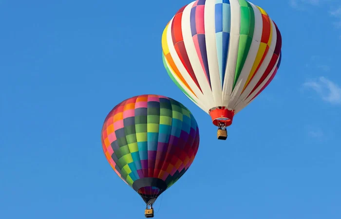 Hot air balloon flying above Marrakech with tourists onboard, offering a stunning view of the cityscape and snow-capped Atlas Mountains